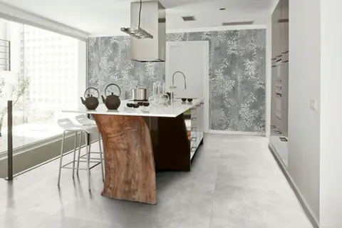 Cucina con isola dal piano in legno grezzo, parete con decoro floreale e pavimento in gres chiaro