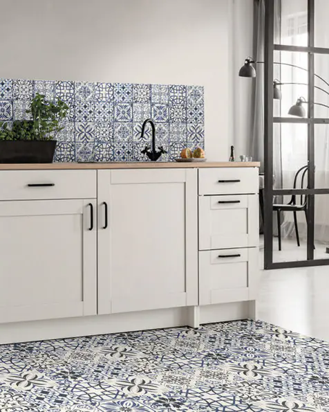 Cucina bianca con paraschizzi decorato e pavimento in cementine blu e bianche che delimita la zona dei mobili