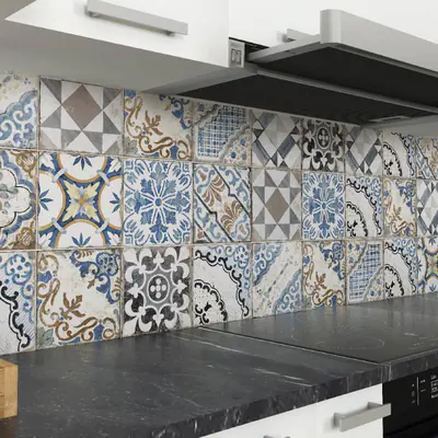 Paraschizzi della cucina in cementine decorate dai toni blu, beige e grigi sopra un piano scuro